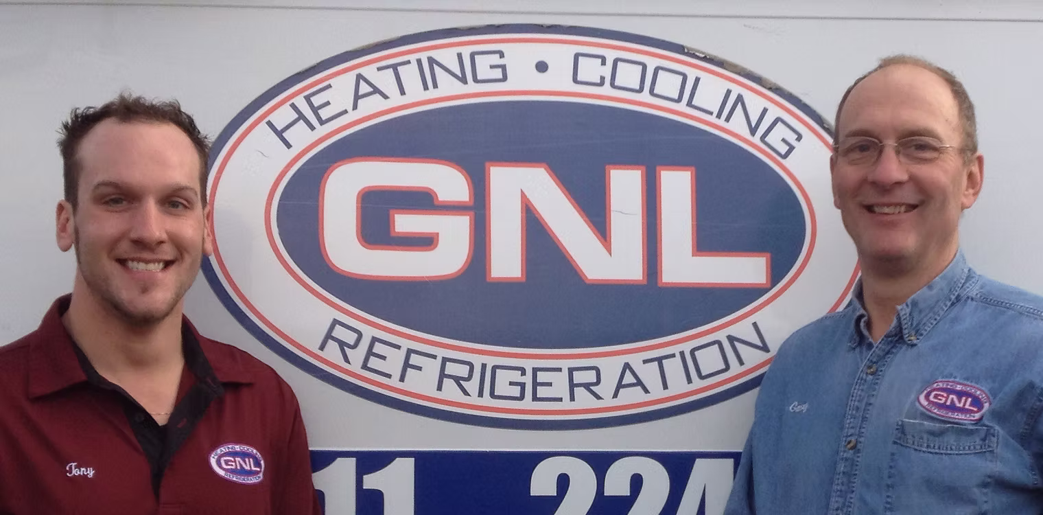 Two GNL Heating and Cooling technicians standing in front of a GNL-branded service van